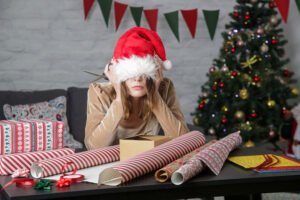 woman feeling stress when trying to wrap Christmas presents